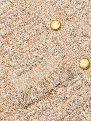 Close-up of the Kastoria Fringe Cardigan’s textured beige and white knit bouclé, featuring two gold “L’AGENCE” buttons and a fringed pocket detail.