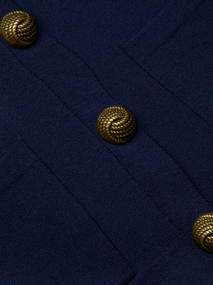 Close-up of the Britt Statement Shoulder Cardigan in navy blue, showcasing three ornate, braided gold buttons and a power stretch knit fabric.