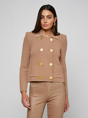 A woman wears the Charlie Knit Jacket, a tailored tan blazer with gold buttons and matching pants, standing against a light gray background and looking directly at the camera with a neutral expression.