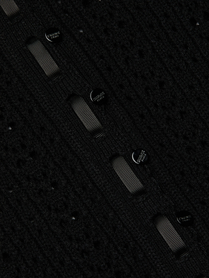 Close-up of the Ninette Knit Top in textured black pointelle fabric, featuring vertical stripes with evenly spaced round black Carven Knit buttons and a dotted perforated pattern for subtle Parisian flair.