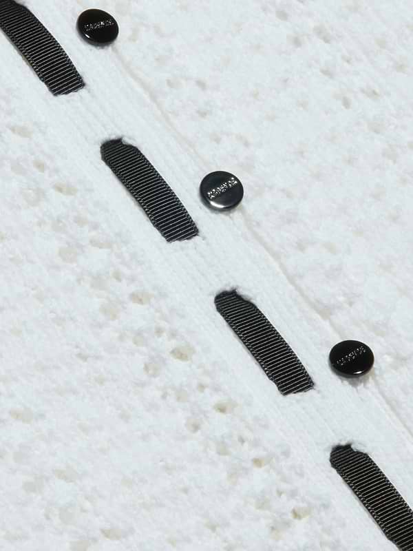 Close-up of the Ninette Knit Top, featuring textured white fabric, three black round buttons, and parallel grosgrain ribbon trims stitched vertically for a touch of Parisian flair.