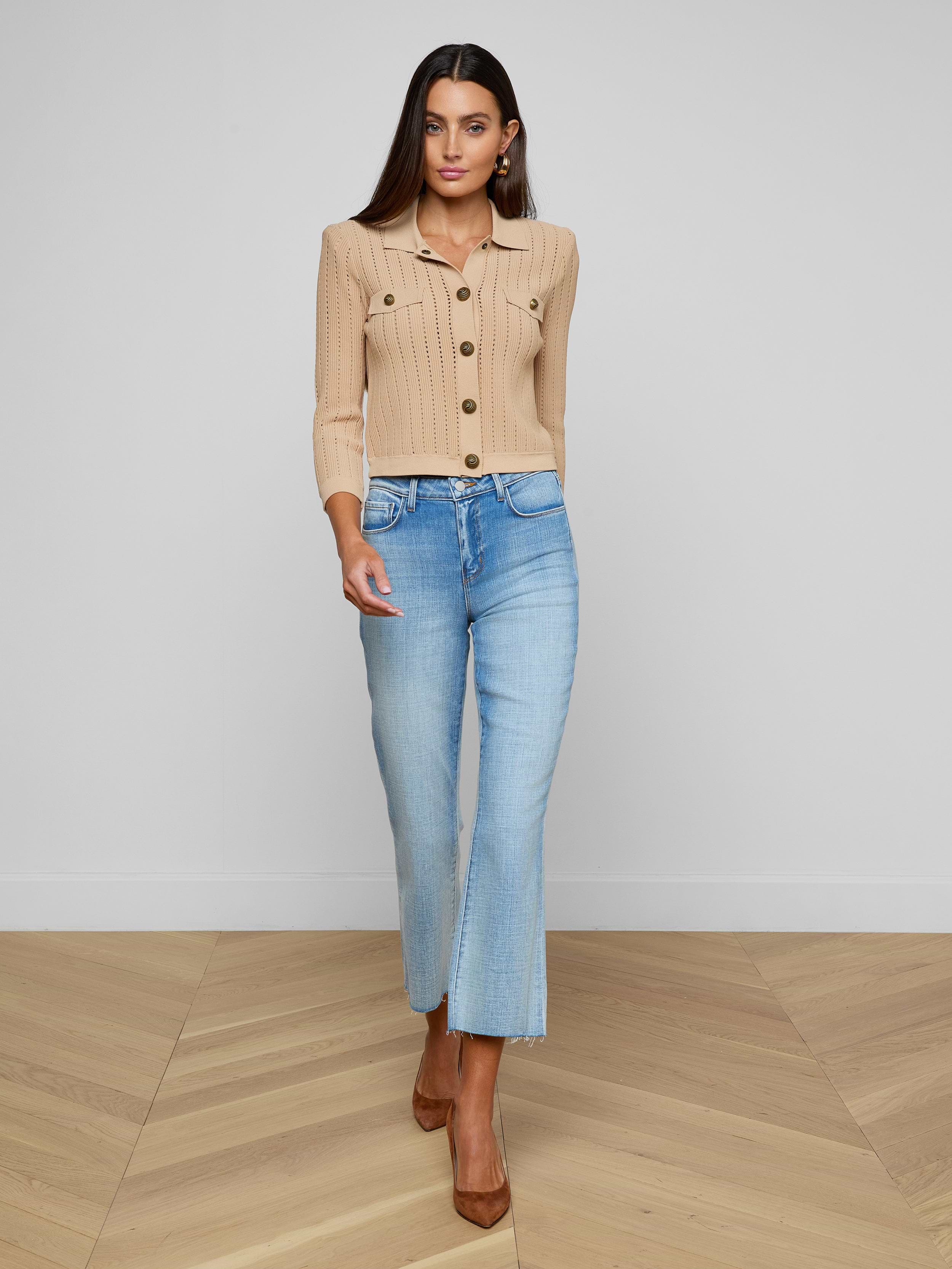A woman wearing the Risa Collared Cardigan in beige, light blue cropped jeans, and brown heels walks forward against a plain white background.