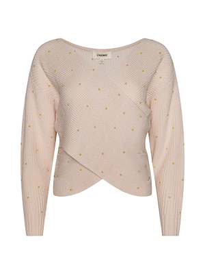 The Antonella Crossover Sweater is a light pink knit with long sleeves, a wrap-style front, and small yellow polka dots scattered evenly across the fabric.