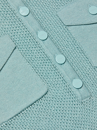 Close-up of the Carine Top in light blue, a lightweight knit with mesh pattern, button placket featuring four round buttons, and two angled flap pockets—all crafted from matching light blue material.