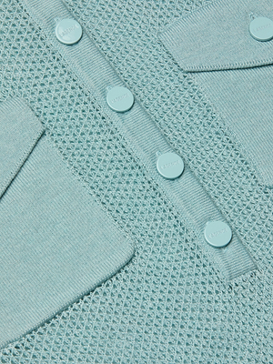 Close-up of the Carine Sweater in light blue, showing off its lightweight knit with a mesh-like pattern, two angled pockets, and a central button placket that add detail to its soft, textured design.
