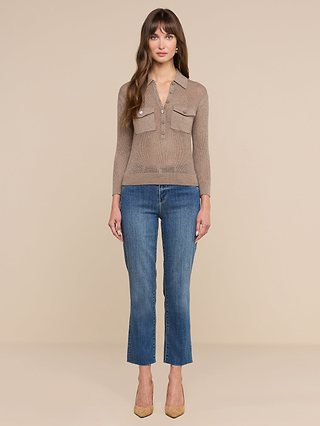 A woman faces forward against a beige background, wearing the light brown Carine Top with utility pockets, blue cropped jeans, and tan high-heeled shoes.