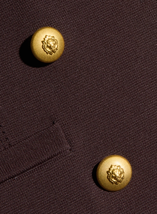 Close-up of the Amelia Knit Blazer in dark brown, showcasing its structured knit fabric, two gold floral-design buttons, and a small left-side pocket.