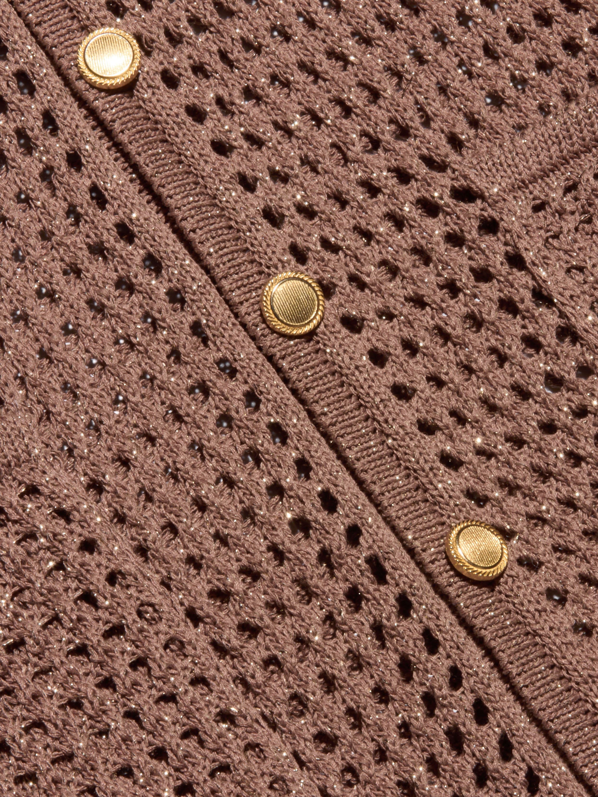Close-up of the Mariana Pointelle Knit Shirt in brown, showcasing its airy, mesh-like pointelle pattern and a row of three round gold buttons along a ribbed edge.