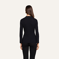A woman with straight brown hair stands facing away, wearing the fitted black Kaye Cardigan Top and black pants, against a plain light background.