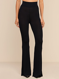 A person wears the Conan Knit Pant, a high rise black ribbed knit flared style, against a plain white background. Only the body from the waist down is visible.