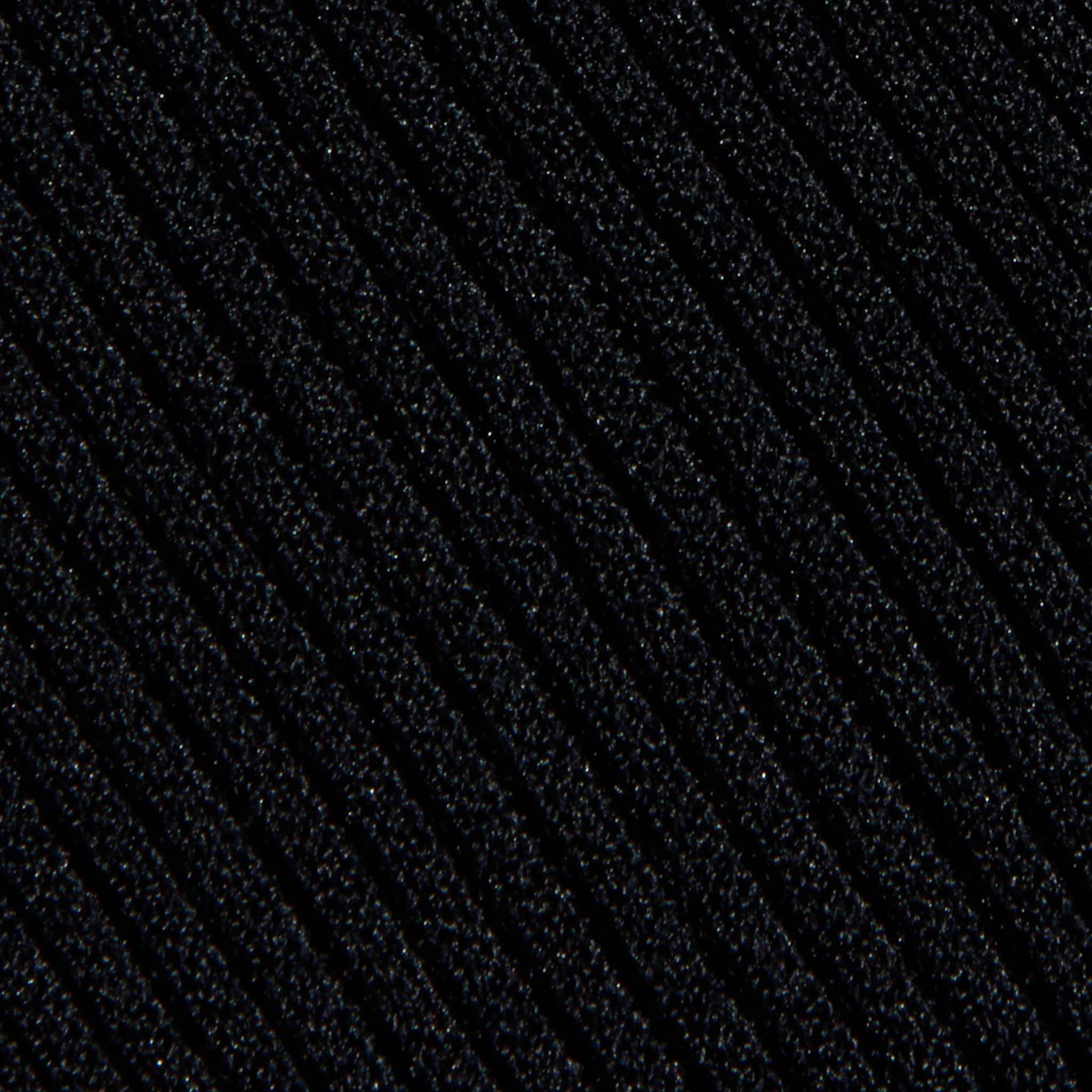 Close-up of the Conan Knit Pant’s textured black knit fabric, featuring diagonal ribbed lines that run across the surface. The lighting accentuates the raised ridges, adding depth and dimension to the material.