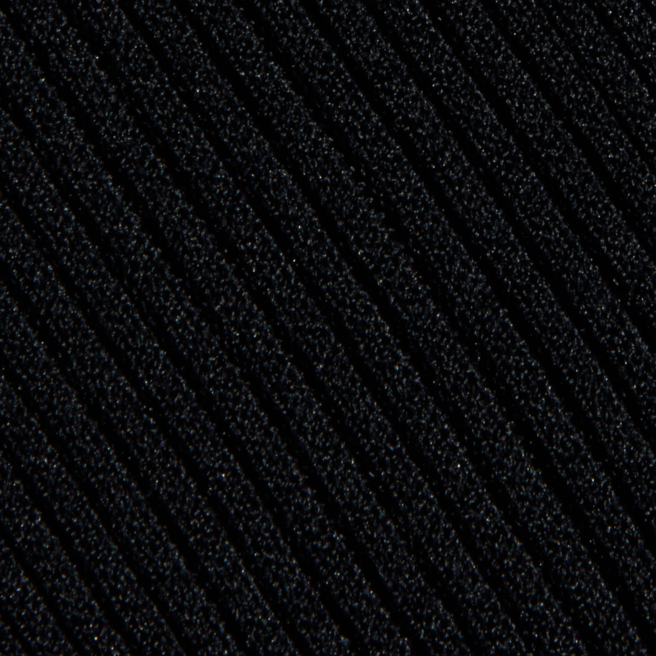 Close-up of the Conan Knit Pant’s textured black knit fabric, featuring diagonal ribbed lines that run across the surface. The lighting accentuates the raised ridges, adding depth and dimension to the material.