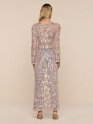 A person with long blonde hair stands facing away, wearing the Sanya Crocheted Cardigan and heeled shoes. The cardigan is sparkling, long-sleeved, and floor-length. The background is plain and white.