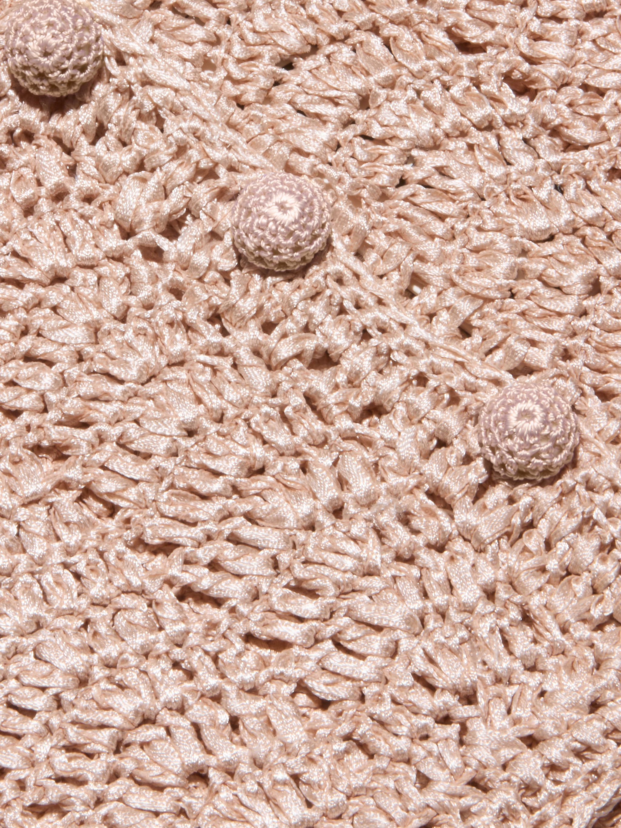 Close-up of the Fey Crocheted Top in beige, featuring textured crochet fabric and three round, raised crochet buttons aligned diagonally across the surface, highlighting the handmade artistry of this piece.