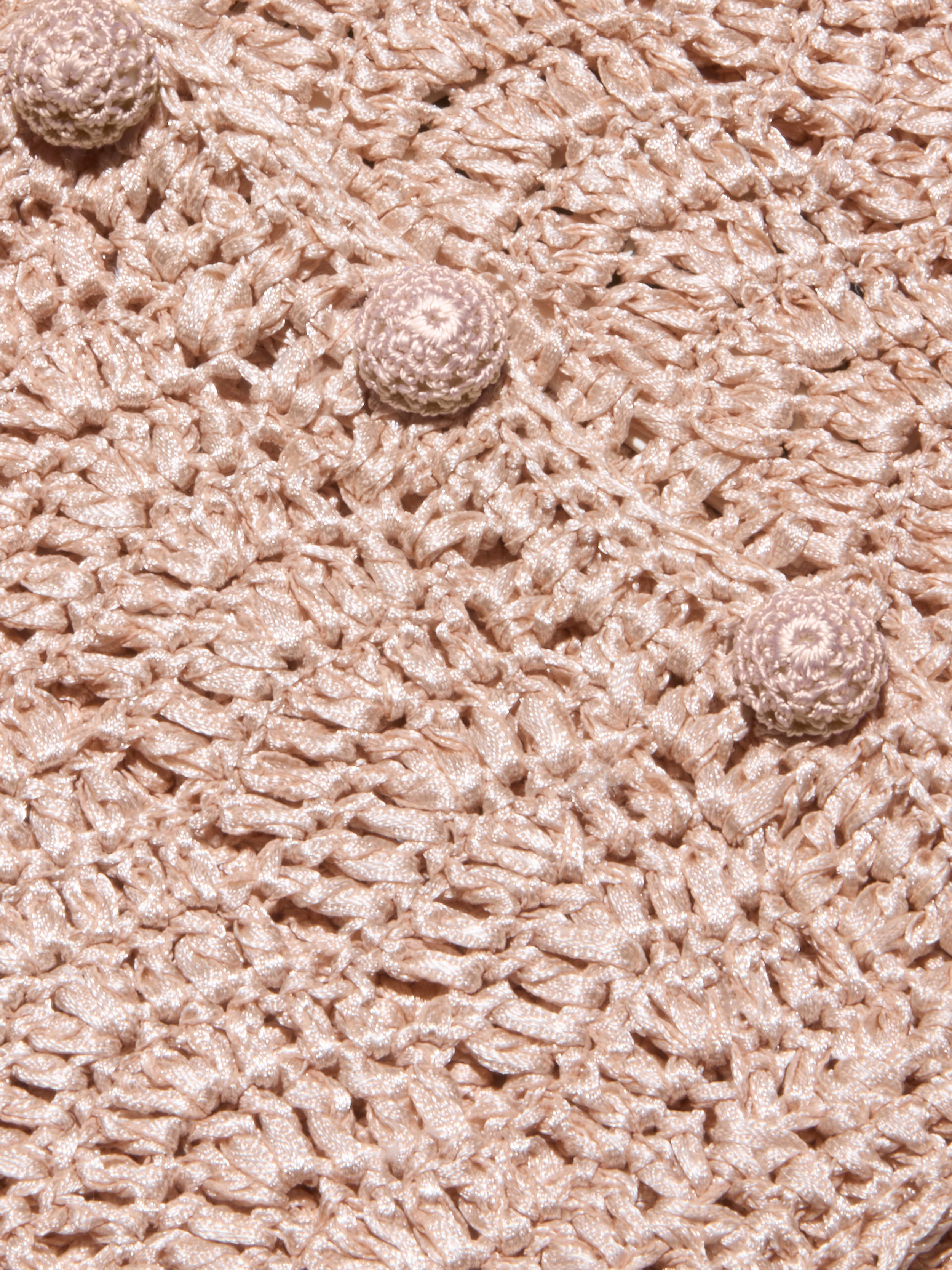 Close-up of the Fey Crocheted Top in beige, featuring textured crochet fabric and three round, raised crochet buttons aligned diagonally across the surface, highlighting the handmade artistry of this piece.