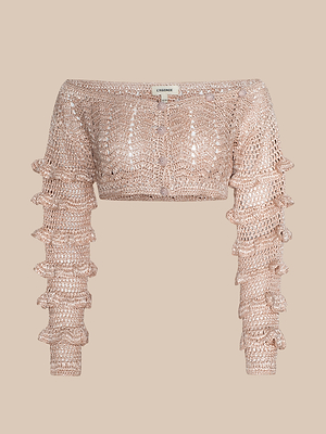 The Fey Crocheted Top is a light beige, cropped, off-the-shoulder knit sweater with long sleeves, ruffled detailing, and a textured open-knit pattern for a handmade feel.