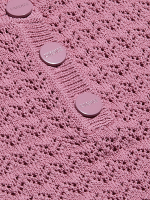 Primo piano del tessuto a maglia pointelle rosa testurizzato del Carven Pointelle Knit Tank, con tre bottoni rotondi rosa chiaro incisi a LAVERNE cuciti in fila su una sezione a coste.