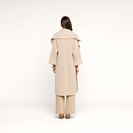 A woman with long brown hair stands facing away, wearing the Orielle Cardigan—beige with a wide collar—paired with beige wide-leg pants and brown heels against a plain white background.