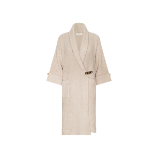 The Orielle Cardigan is a wool knit cardigan in beige, featuring long sleeves with rolled cuffs fastened by buttoned tabs, front pockets, and a wide collar. Its wrap design is secured with a small brown side buckle, making it an ideal choice for fall fashion. The cardigan is presented against a plain white background.