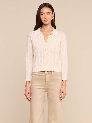 A woman wearing the Airy Cable Knit Sweater, featuring a cream color, heart-shaped buttons, and a high collared neckline, paired with beige high-waisted pants, stands against a neutral background.
