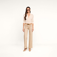 A woman wearing sunglasses and the Airy Cable Knit Sweater—a beige long-sleeve cable knit top with heart buttons—paired with tan wide-leg belted pants and tan heels stands against a plain white background.