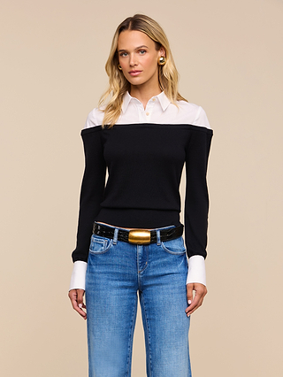 A woman wears the Mathilde Poplin Collar Pullover layered under a black off-the-shoulder sweater, paired with blue jeans and a black belt with a gold buckle, standing against a plain beige background.