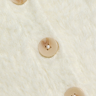 Close-up of three beige buttons with a subtle marbled pattern, sewn in a vertical line onto the soft, cream-colored fuzzy fabric of the Agathe Cardigan Top.