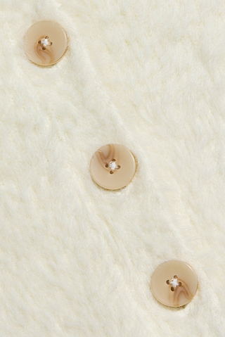 Three beige marbled buttons sewn vertically onto the soft, cream-colored Agathe Cardigan Top, shown in close-up detail.