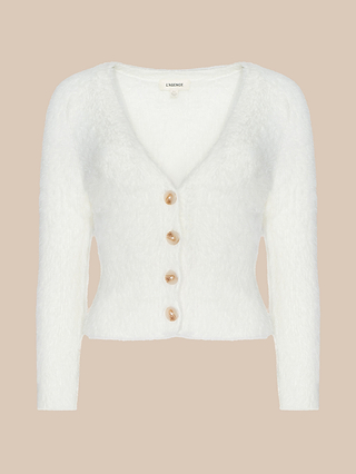 The Agathe Cardigan Top is a white fuzzy long-sleeve cropped cardigan featuring a deep V-neck and four large tan buttons down the front, displayed on a beige background.