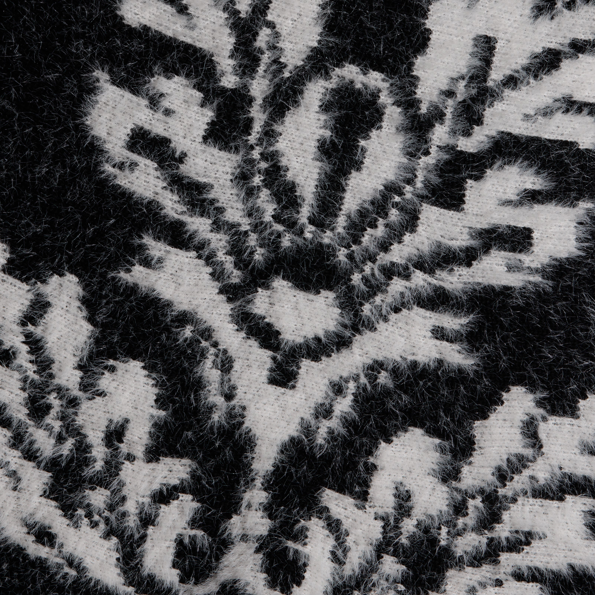 Close-up of the black and white fuzzy knit fabric of the Naiad Jacquard Fringe Cardigan, featuring a relaxed-fit floral pattern.