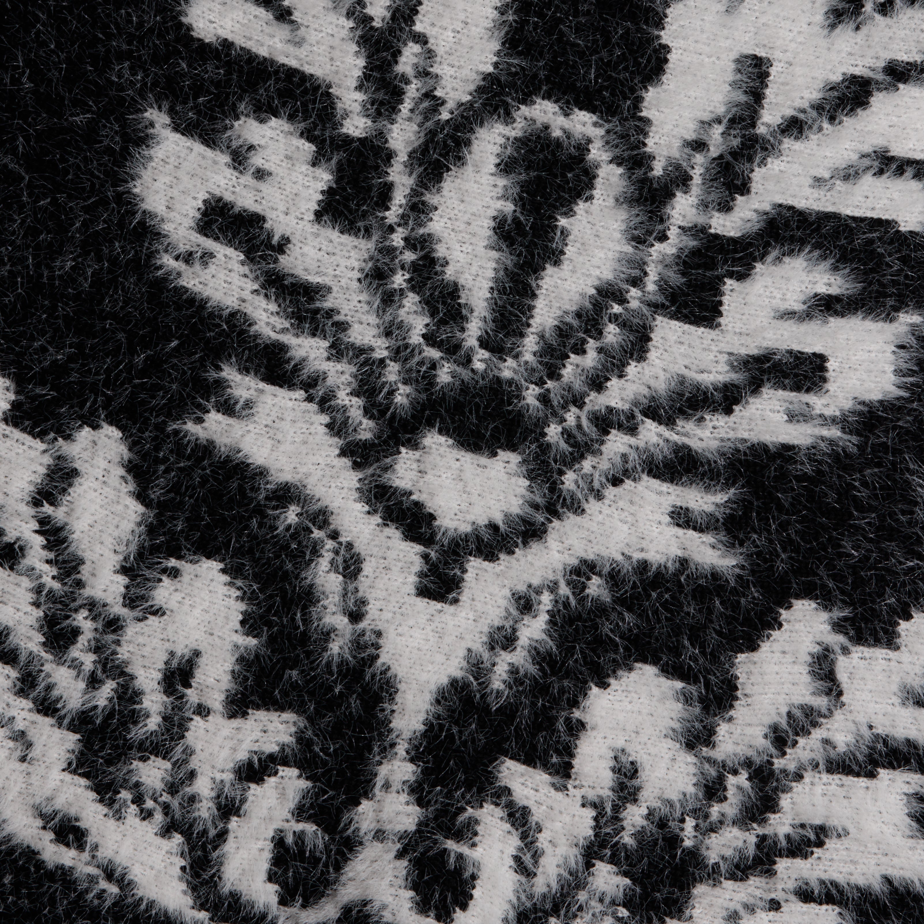 Close-up of the black and white fuzzy knit fabric of the Naiad Jacquard Fringe Cardigan, featuring a relaxed-fit floral pattern.