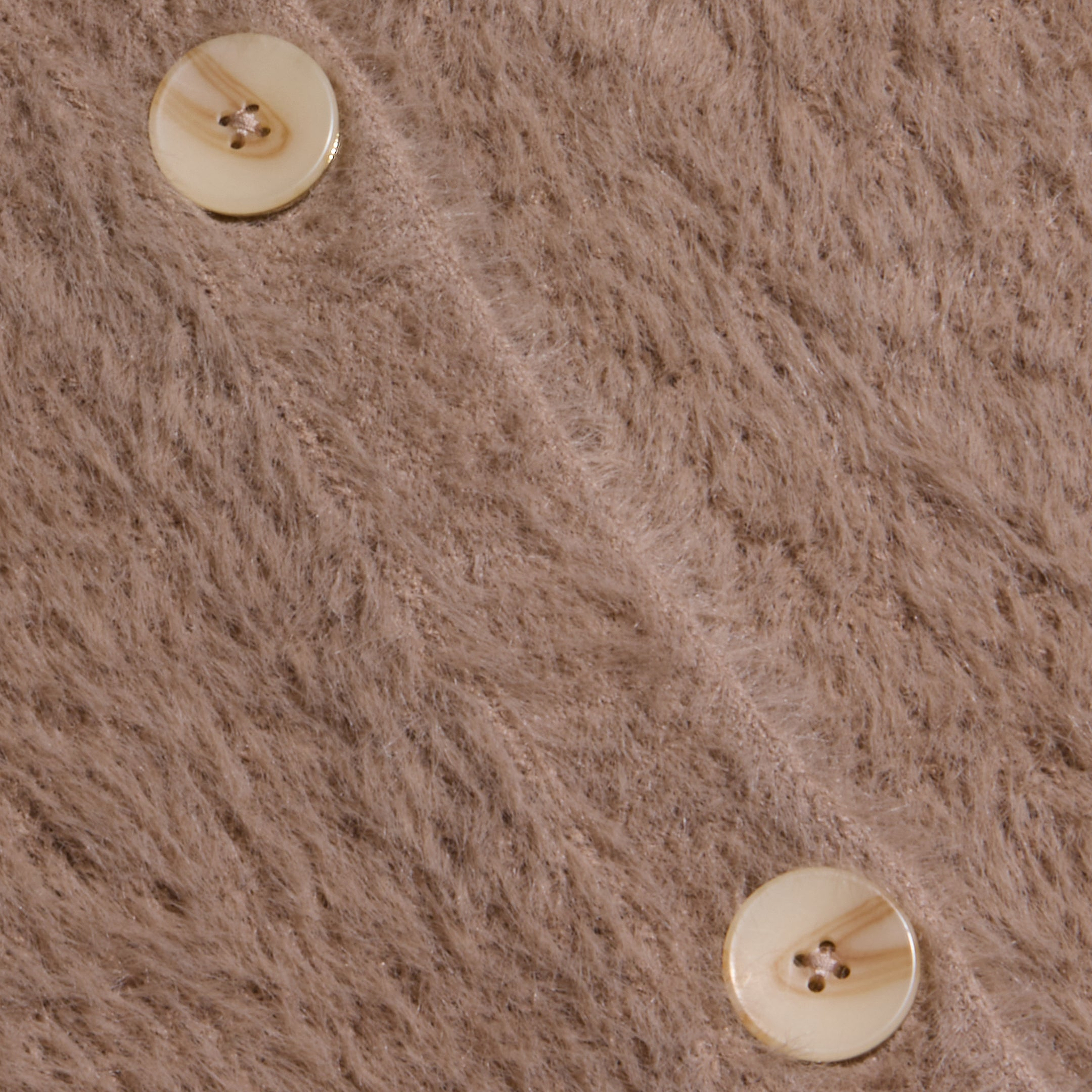 Close-up of two cream-colored buttons on the soft, fuzzy light brown fabric of the Mist Cardigan, with a diagonal seam running between the buttons.