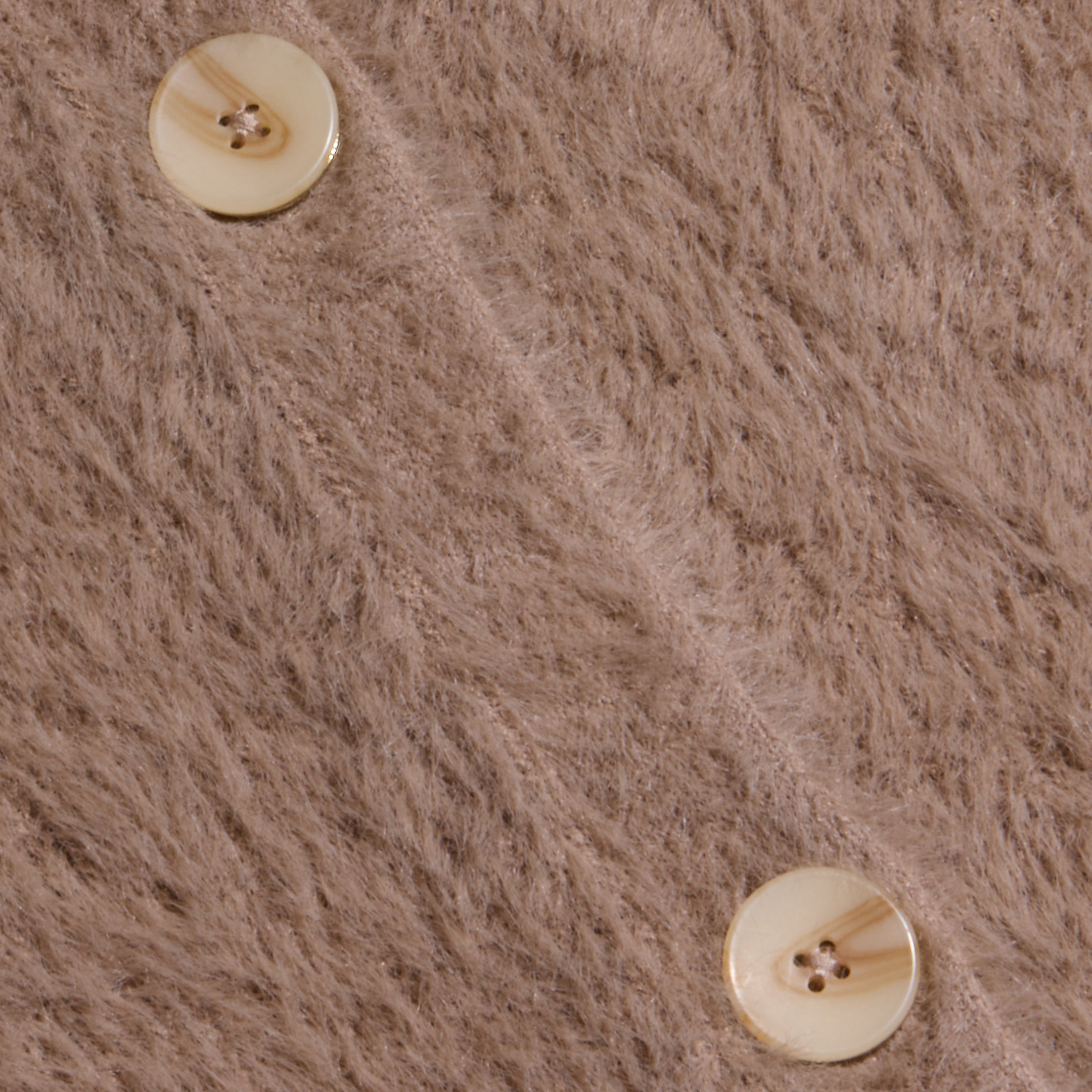 Close-up of two cream-colored buttons on the soft, fuzzy light brown fabric of the Mist Cardigan, with a diagonal seam running between the buttons.