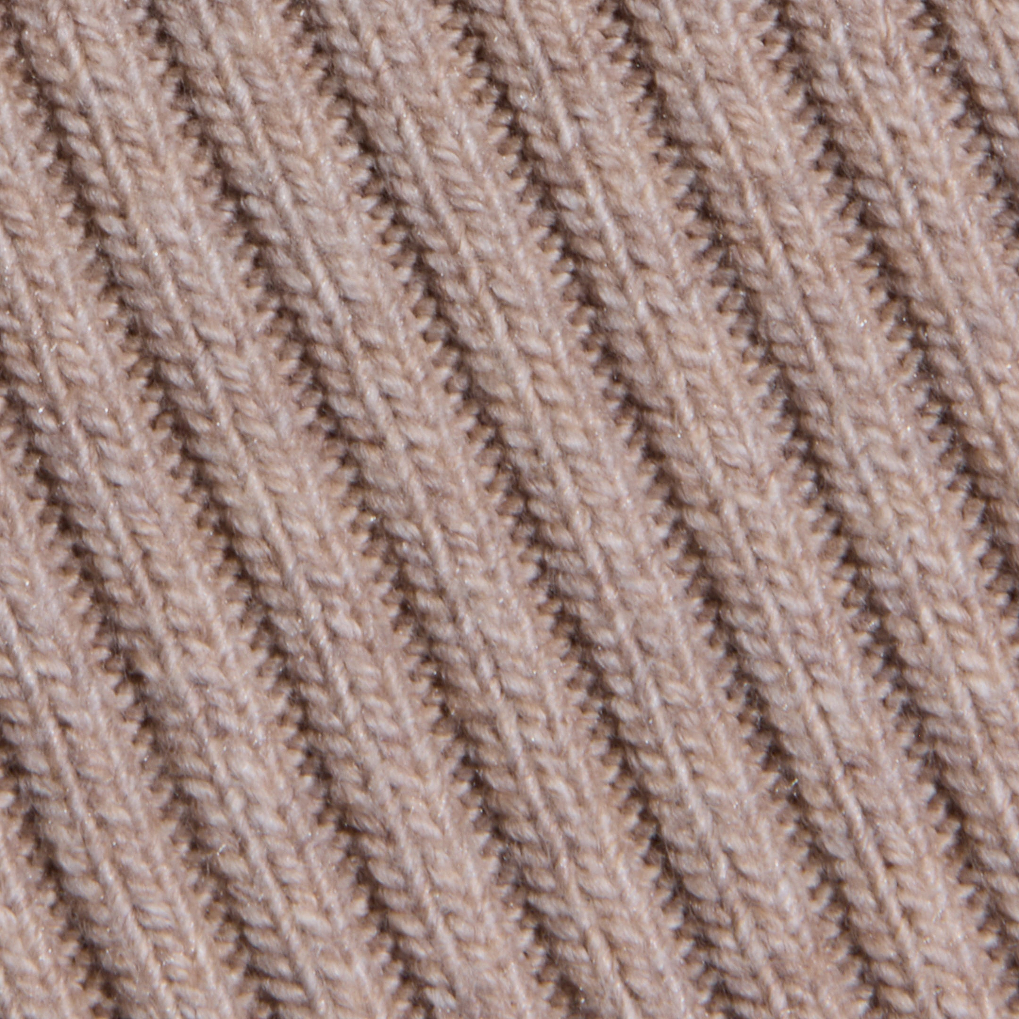 Close-up of the Hail Cabled Cardigan’s beige, ribbed knit fabric, featuring diagonal lines and textured stitching that evoke the cozy charm of classic cable knits.