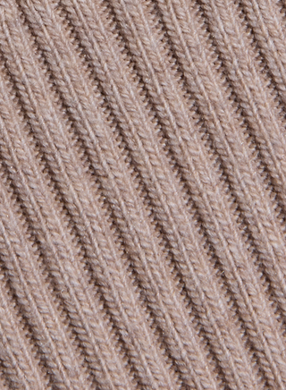 Close-up of beige ribbed fabric with diagonal textured lines, highlighting the fine knit details and uniform stitching characteristic of the Hail Cabled Cardigan.