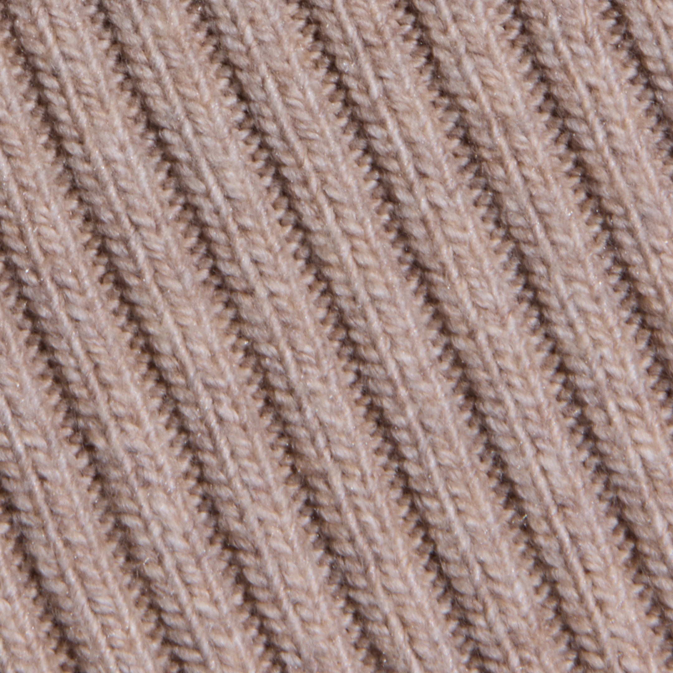 Close-up of the Hail Cabled Cardigan’s beige, ribbed knit fabric, featuring diagonal lines and textured stitching that evoke the cozy charm of classic cable knits.