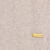 A small gold tag engraved with LAGENCE is attached to the Nimbus Pullover, featuring a soft, light beige, textured fabric reminiscent of a cloud-soft sweater crafted from ultra-soft yarn.