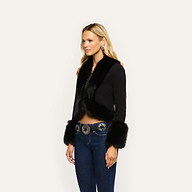 Irma Cardigan, a cropped black Y2K style with faux fur trim on the collar and cuffs, worn with dark blue jeans and a silver concho belt.