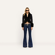 The Irma Cardigan, a black Y2K cropped piece with faux fur trim on the collar and cuffs, worn with dark-wash flared jeans and a decorative western-style belt.