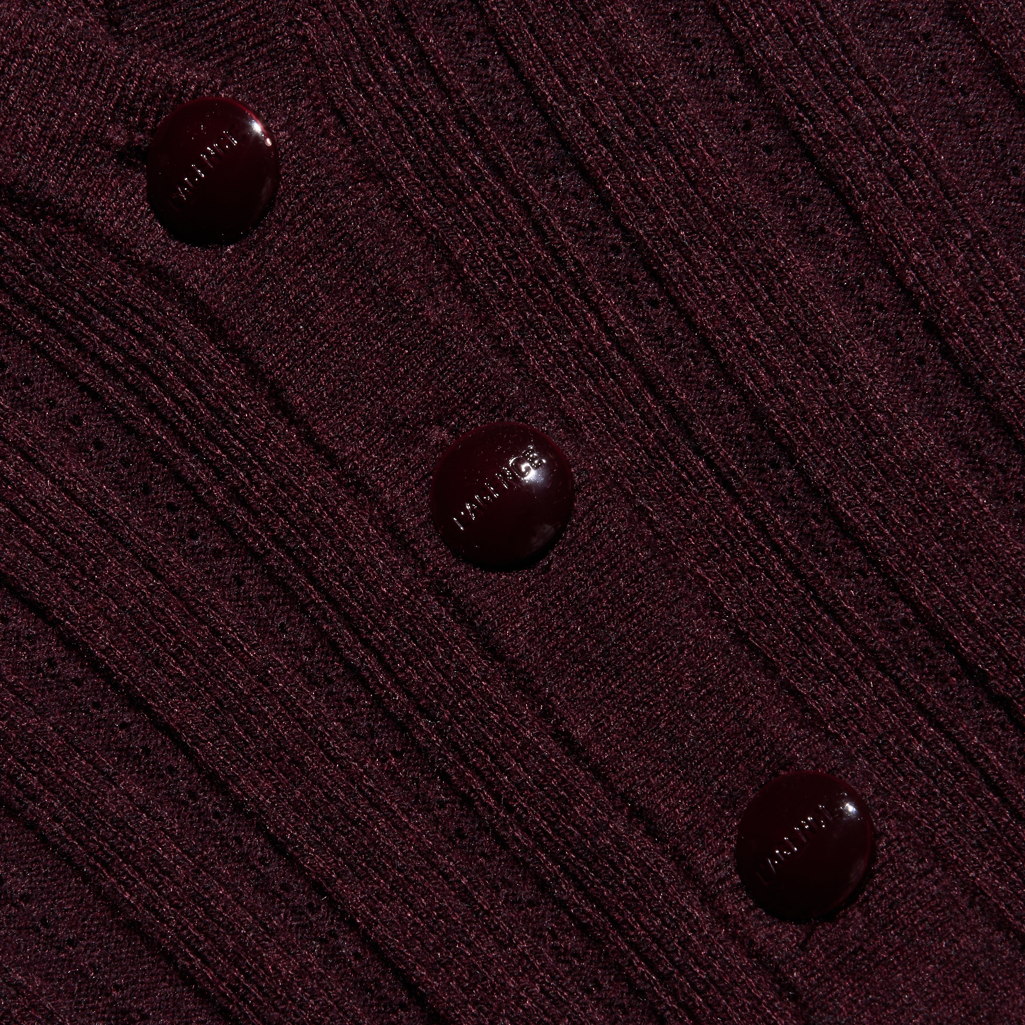 Close-up of a maroon, lightweight ribbed knit Finian Cardigan Top, cropped with three matching round buttons down the front.