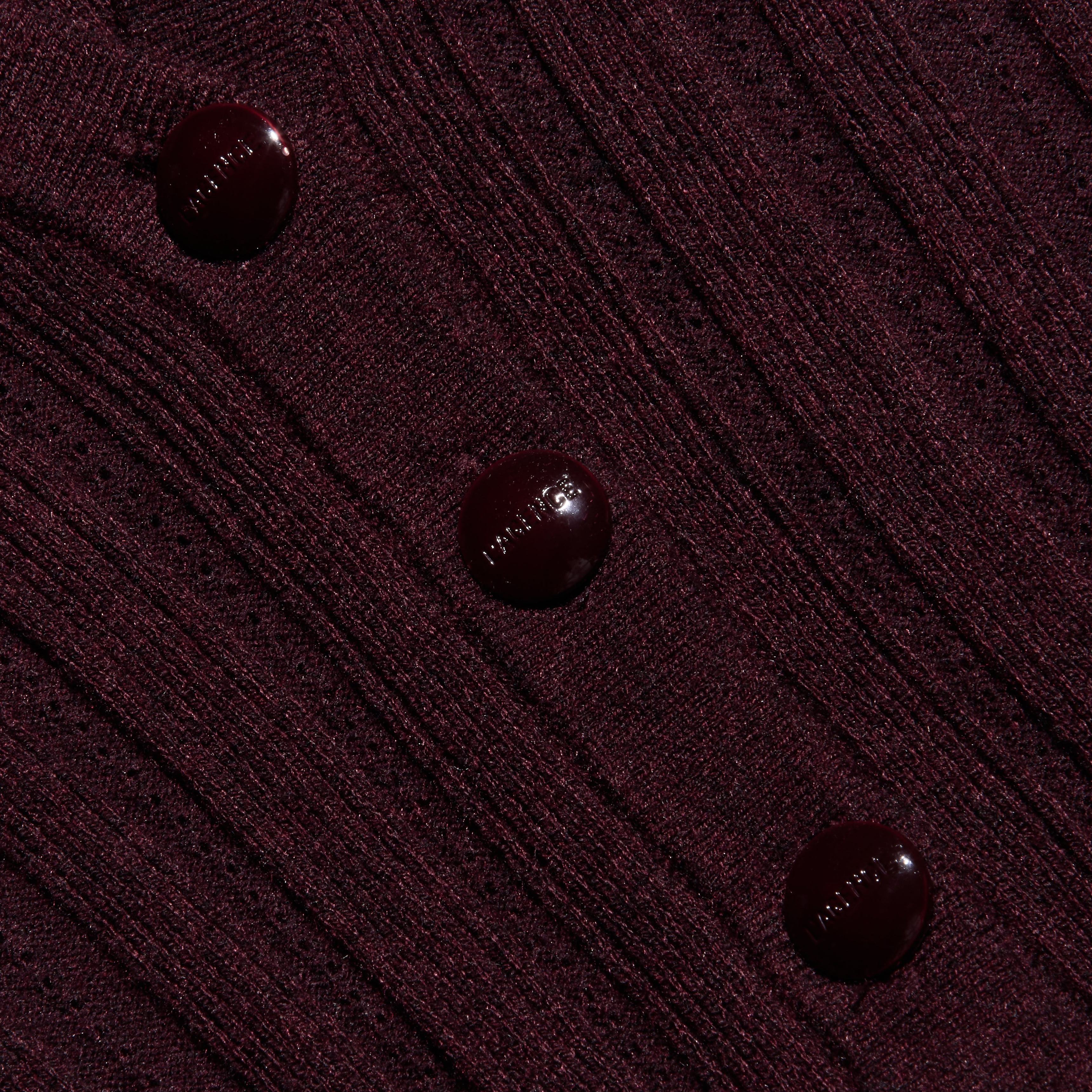 Close-up of a maroon, lightweight ribbed knit Finian Cardigan Top, cropped with three matching round buttons down the front.