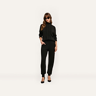 A person wears a black cable-knit sweater and matching Tamaris Cable Knit Pant with black heels and sunglasses.