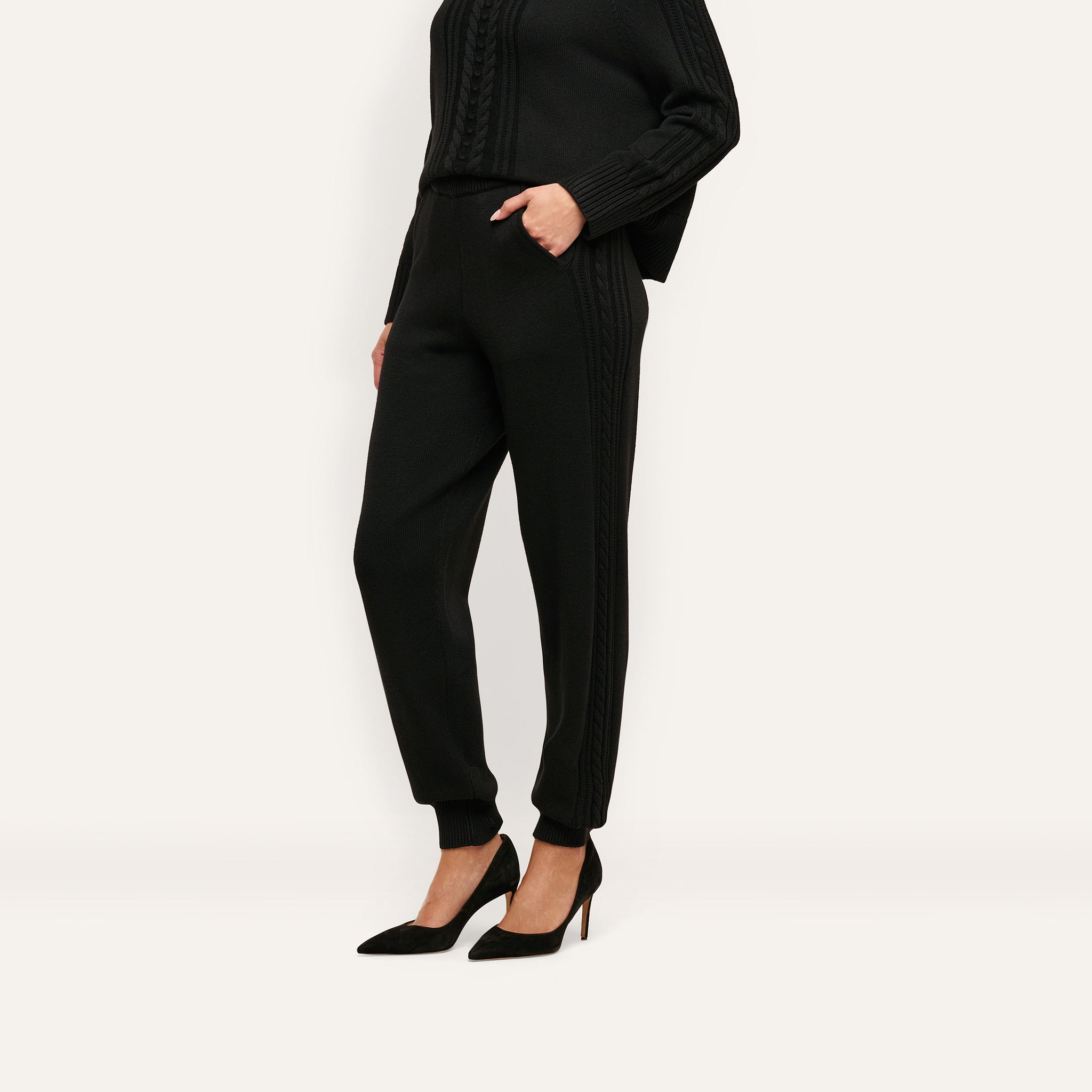 A person wearing black Tamaris Cable Knit Pant slim-fit trousers with ribbed cuffs and matching black high heels.