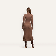 A person seen from behind, wearing a brown, long-sleeved, funnelneck Solaire Knit Dress in a lightweight midi knit paired with dark knee-high heeled boots.