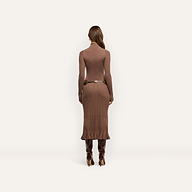 Back view of a person wearing a brown Solaire Knit Dress, a lightweight knit funnelneck midi design with a ribbed skirt, a thin metallic-buckle belt, and knee-high heeled boots.