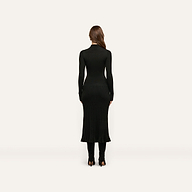 A woman seen from behind wearing a black long-sleeved mock-neck fitted Solaire Knit Dress with a ribbed skirt and black heeled boots.