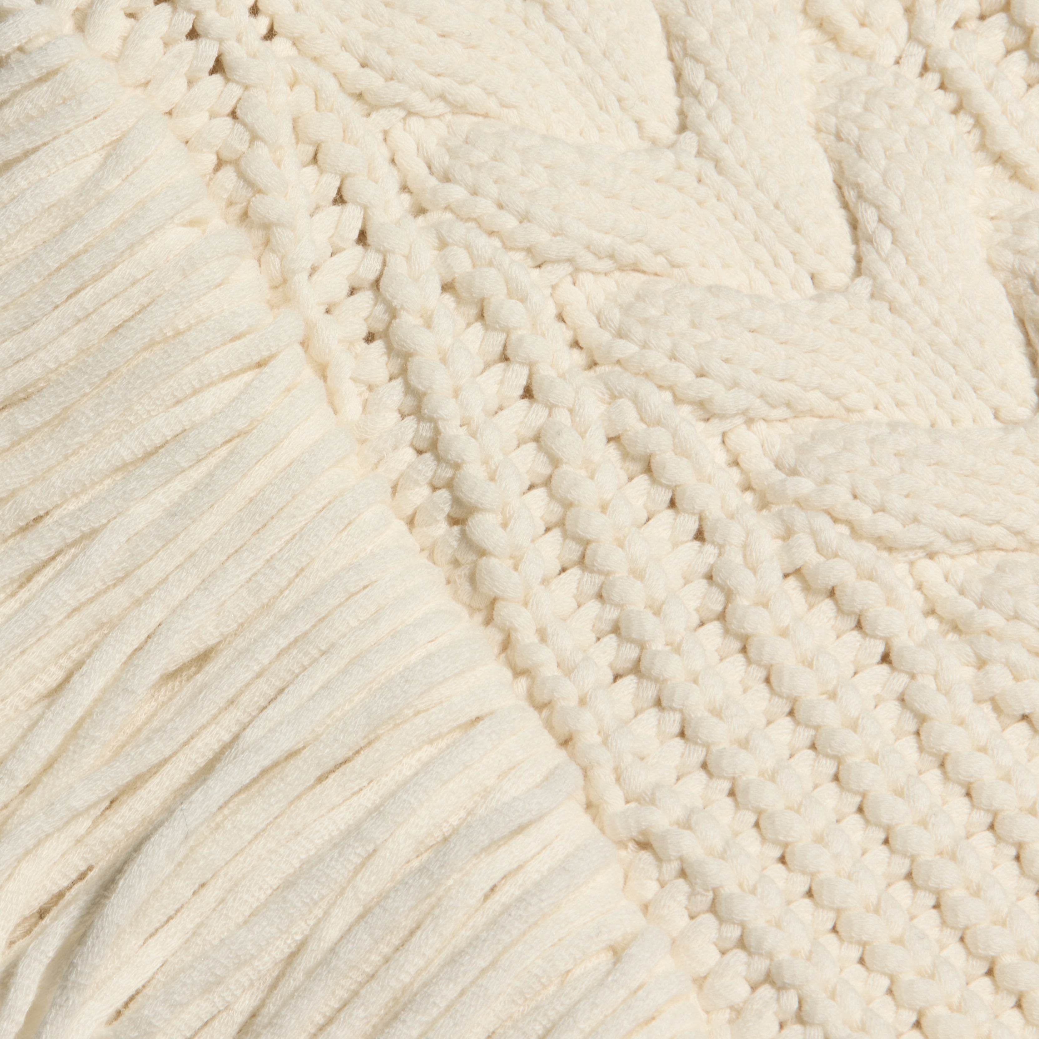 Close-up of an Ottavia Pullover, a chunky, off-white cable knit sweater featuring a combination of ribbed trim and a braided pattern.