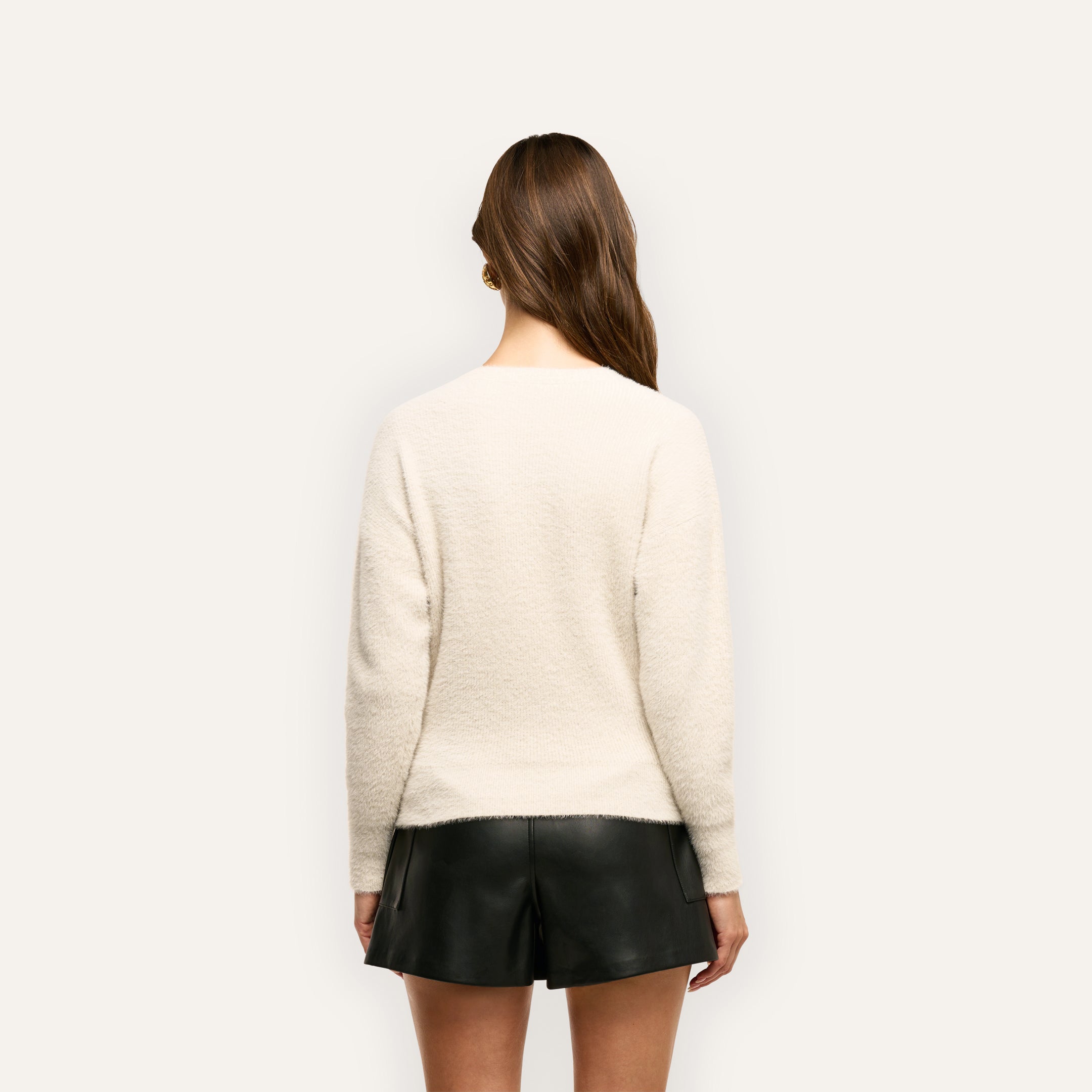 A person seen from behind wearing a vintage white soft knit Korinna Pullover and black shorts.