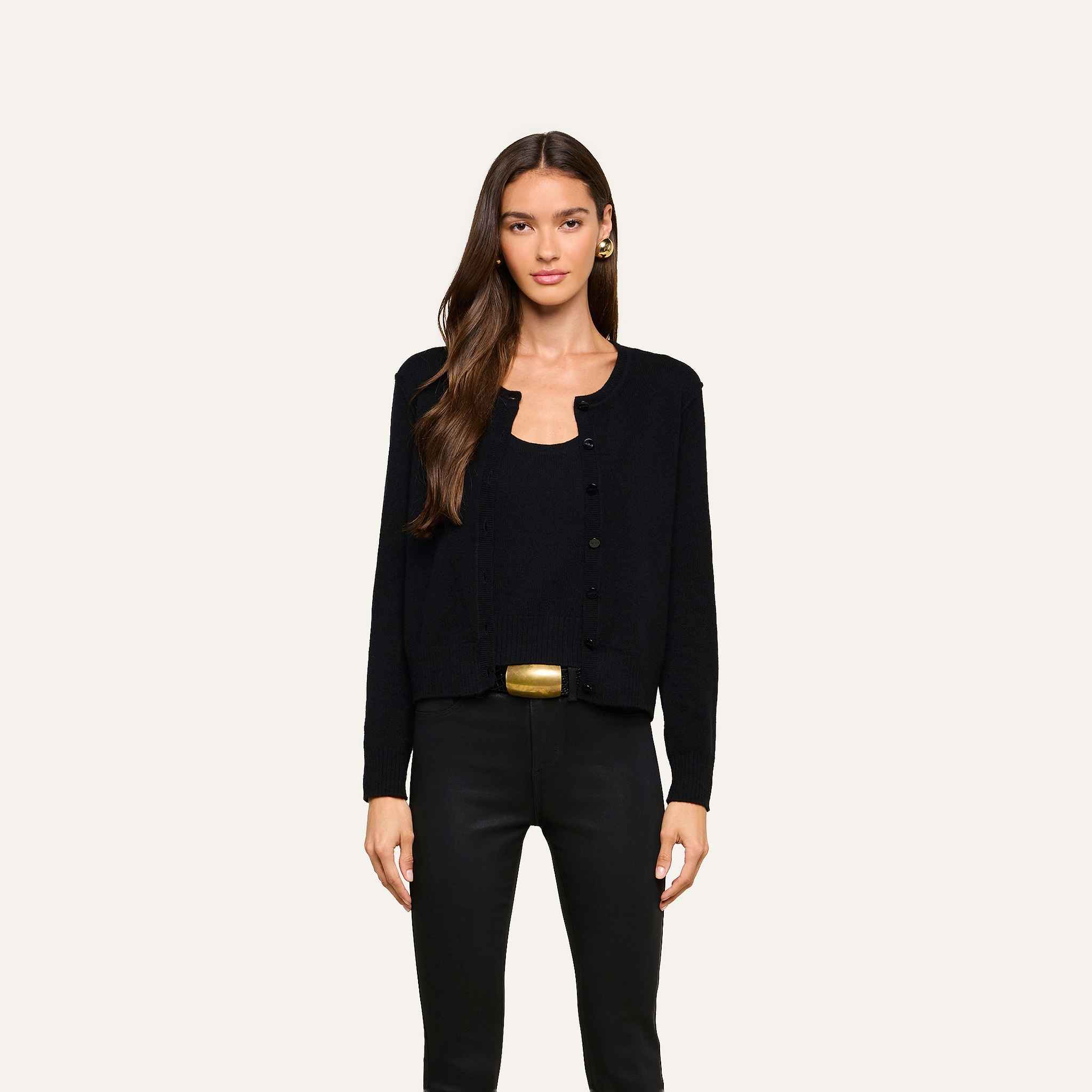 A woman with long brown hair wears the Malone Cashmere Cardigan in black over a matching top and black pants, standing against a plain light background.