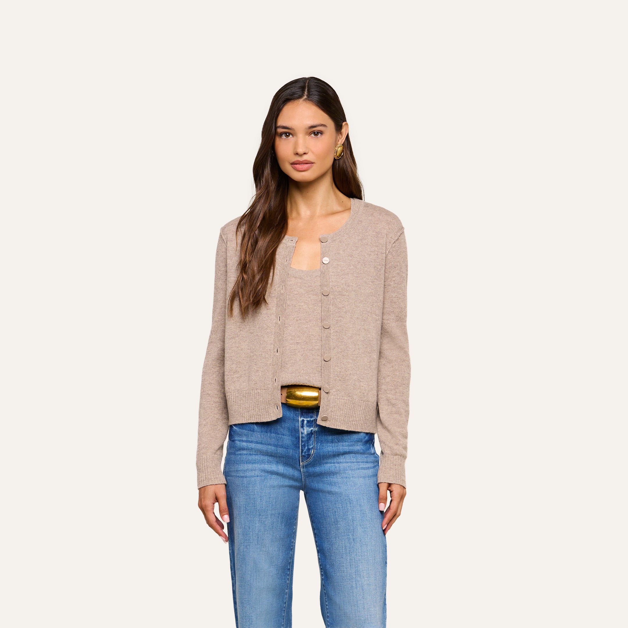 A woman with long brown hair wears the Malone Cashmere Cardigan over a matching top and blue jeans, standing against a plain light background.
